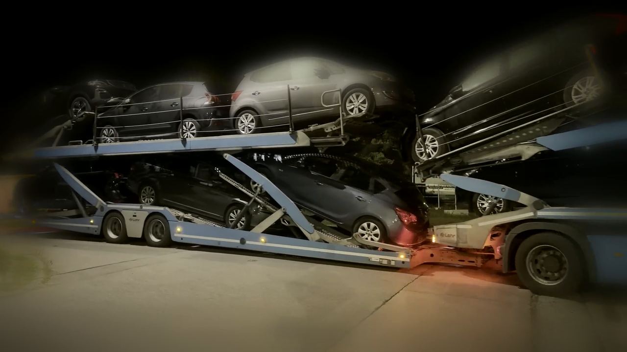 Nagranie: czerwony autotransporter Volvo Kol-Trans z samochodami na naczepie, nocą na placu załadunkowym w Belgii